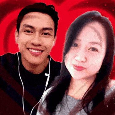 a man and a woman are posing for a picture with a red heart behind them