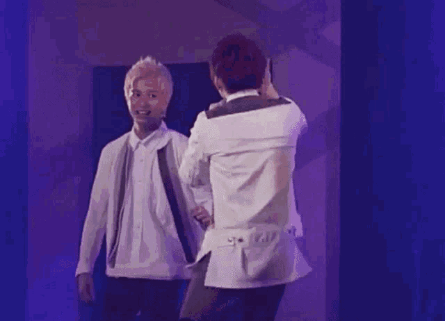 a man in a white shirt is holding another man 's arm while standing on a stage .