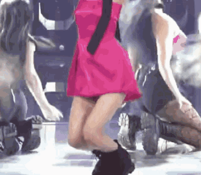 a woman in a pink dress is dancing on a stage with two other dancers .