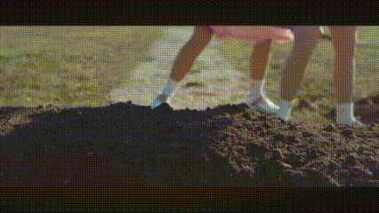 two women are digging a hole in the dirt .