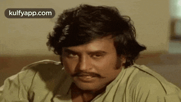 a man with a mustache is looking at the camera .
