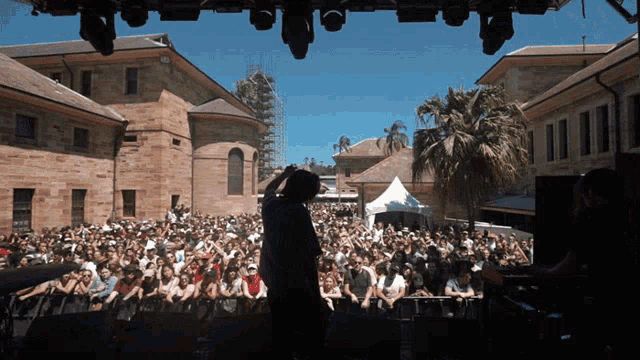 a man stands on a stage in front of a large crowd of people
