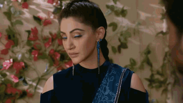 a woman wearing a blue top and blue earrings is looking down .