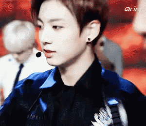 a young man wearing a black shirt and a blue jacket is talking into a microphone ..