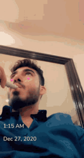 a man with a beard is smoking a cigarette in front of a mirror with the date dec 27 2020