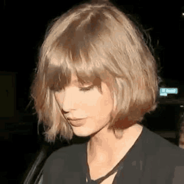 taylor swift is wearing a black dress and a bob hairstyle with bangs .