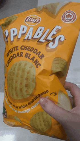a person is holding a bag of appables white cheddar cheddar blanc