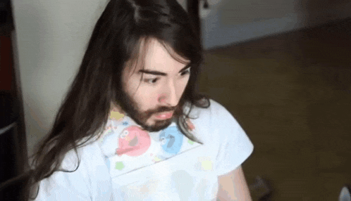a man with long hair and a beard is wearing a bib .