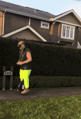 a man riding a unicycle in front of a house with the number 4005 on it