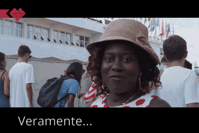 a woman wearing a straw hat stands in front of a building with the words veramente written below her