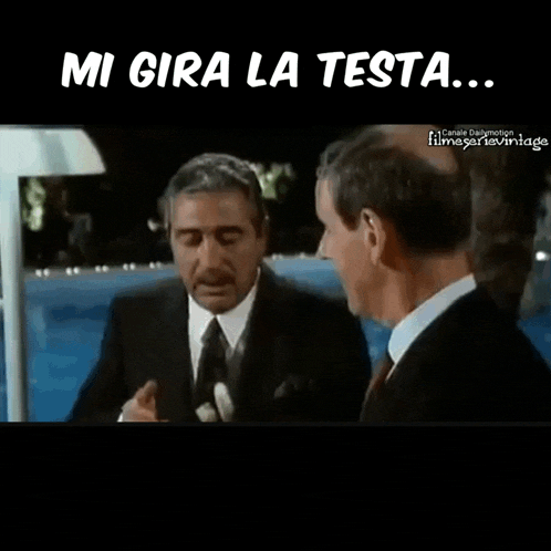 a man in a suit and tie is talking to another man with the caption mi gira la testa
