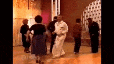 a group of people are dancing together on a dance floor in a room .
