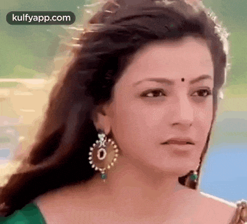 a close up of a woman wearing earrings and a green dress .