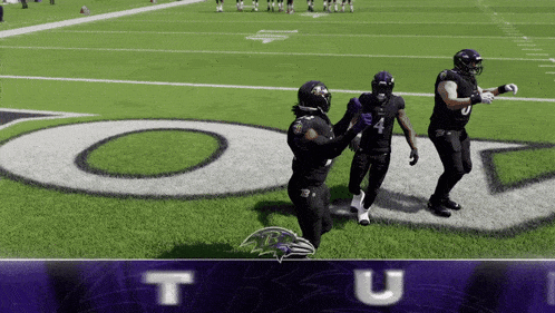 three ravens players are standing on a football field