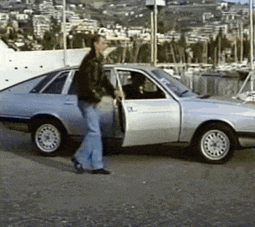a man is standing next to a silver car with the door open
