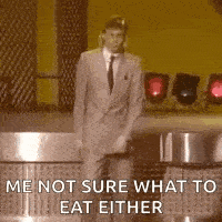 a man in a suit and tie is standing on a stage and saying `` me not sure what to eat either '' .