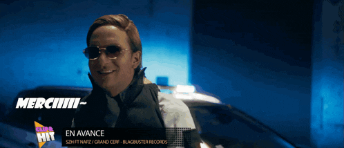 a man wearing sunglasses is standing in front of a car with the words en avance on the bottom
