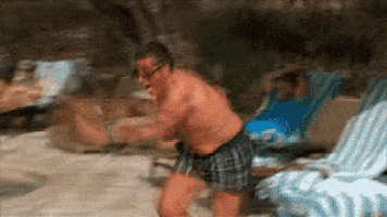 a man without a shirt is dancing on a beach .