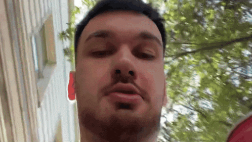 a man with a beard is making a funny face in front of a building