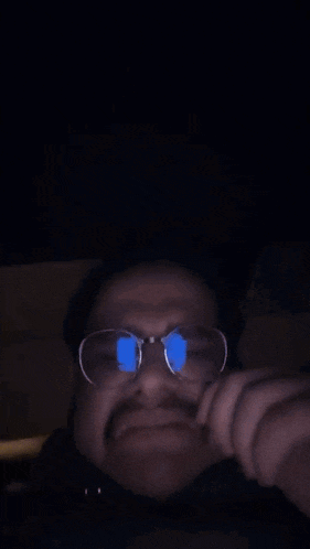 a person wearing glasses covering their face with their hand