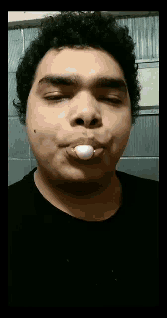 a young man blowing a bubble with a bubble gum in his mouth