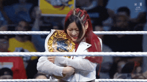 a woman in a wrestling ring holding a championship belt