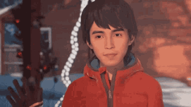 a man in a red jacket stands in front of a christmas tree .