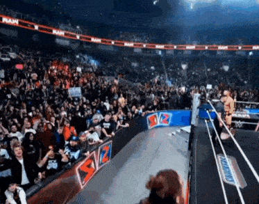 a crowd of people watching a wrestling match in a stadium with a snickers sign