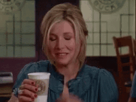a woman in a blue shirt is holding a cup of coffee .
