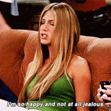 a woman in a green tank top is sitting on a couch and saying i 'm so happy and not at all jealous