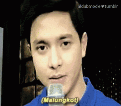 a man in a blue shirt is holding a microphone and says " malungkot "