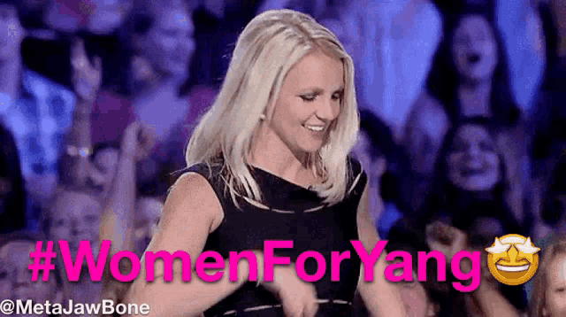a woman in a black dress is dancing in front of a crowd with the hashtag #womenforyang on the bottom