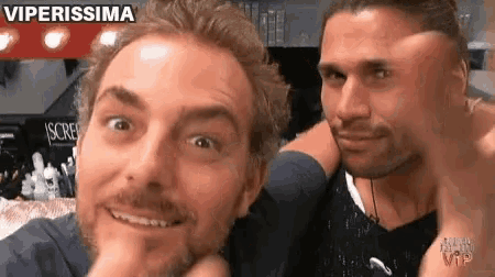 a couple of men are posing for a picture and one of them has a beard .
