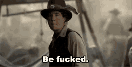 a man in a hat is saying `` be fucked '' while standing in front of a group of people .
