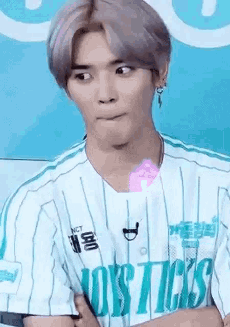a man with purple hair is wearing a striped shirt and making a face .