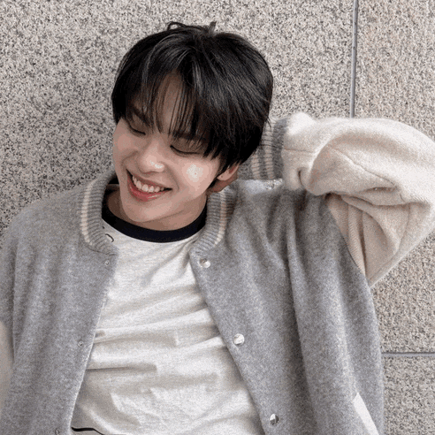 a young man wearing a grey jacket and white shirt smiles