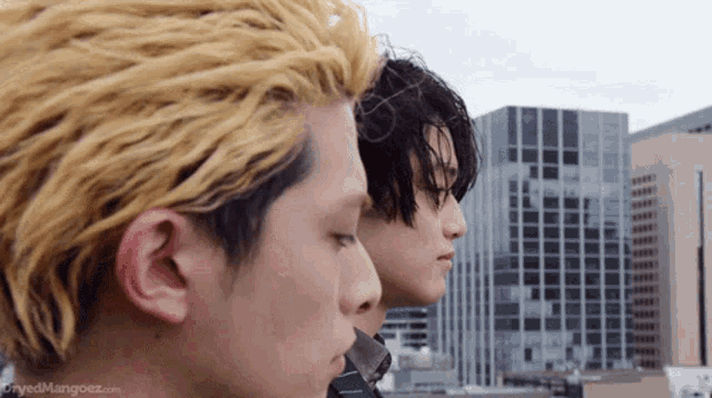 a couple of men standing next to each other with a city in the background