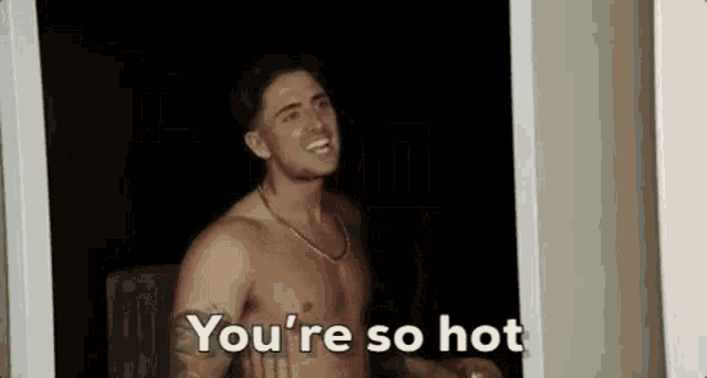 a shirtless man is standing in a doorway talking to someone .