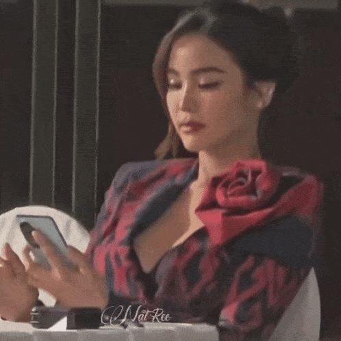 a woman in a red and black jacket is using a cell phone