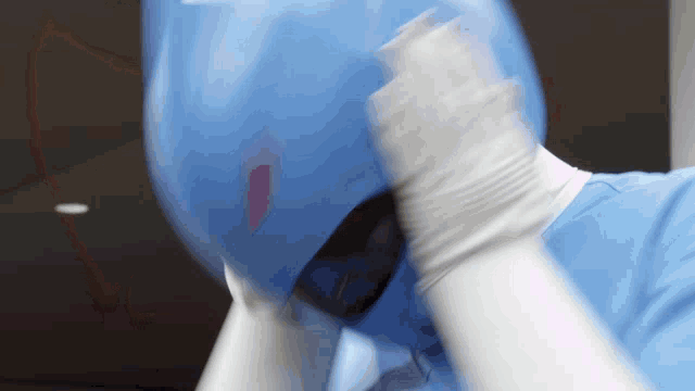 a person wearing a blue helmet and white gloves covering their face