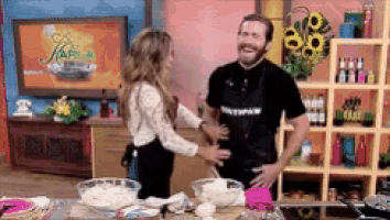 a man and a woman are hugging in a kitchen and the woman is wearing an apron that says pottpaw