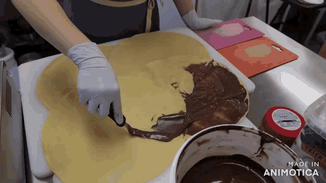 a person is spreading chocolate on a tortilla with a spatula and the words made in animotica visible in the corner