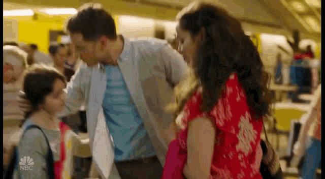 a man is kissing a woman on the cheek while standing next to a woman and a little girl .