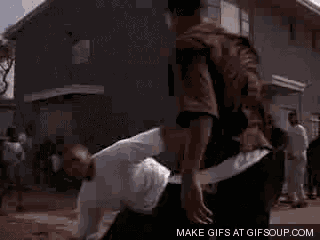 two men are fighting in front of a building in a video .