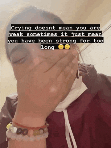 a woman wearing a mask covering her face with her hand and a quote that says crying does nt mean you are weak