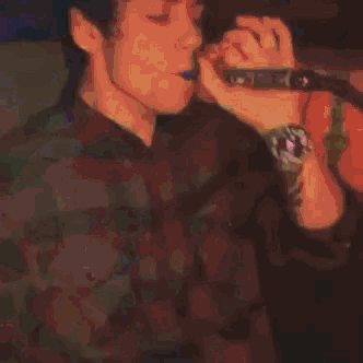 a young man is blowing smoke out of a bottle .