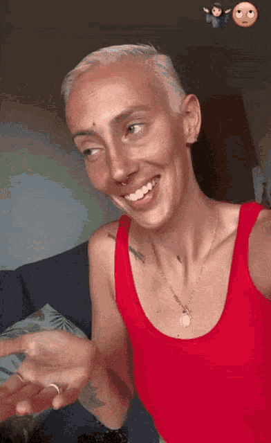 a woman wearing a red tank top and a necklace smiles