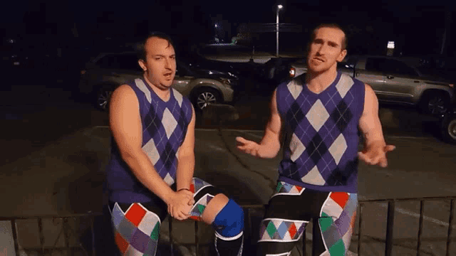 two men wearing argyle sweaters sit next to each other on a railing