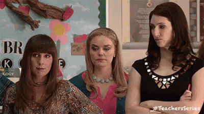 three women are sitting in a classroom with their arms crossed .
