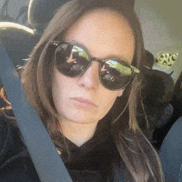 a woman wearing sunglasses and a black shirt is sitting in a car